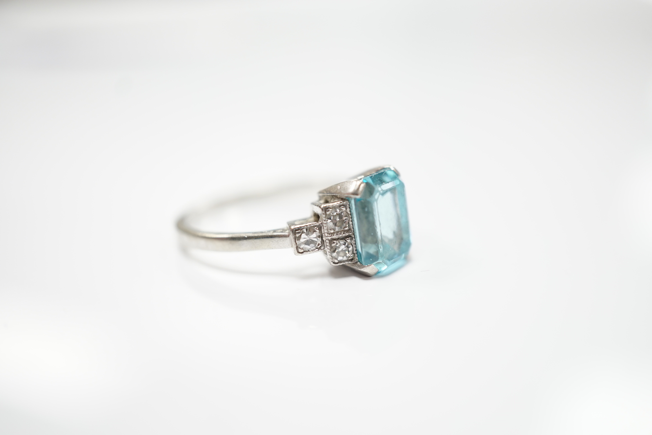 An 18ct, plat and single stone emerald cut blue zircon set ring, with six stone diamond set shoulders, size L, gross weight 2.9 grams.